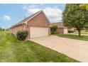 Attached two-car garage showing the long driveway and neatly manicured lawn on a sunny day at 4725 W Harrisburg Ct, New Palestine, IN 46163