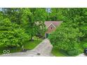A red brick home with a blue garage door nestled among lush green trees and a well-maintained lawn at 5558 Spicebush Dr, Indianapolis, IN 46254