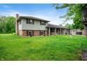Side view of a two-story home showcasing the yard, partial brick facade, and chimney at 5631 N Olivia Dr, Alexandria, IN 46001