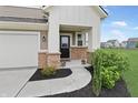 Inviting home entrance with well-maintained landscaping, a black front door, and charming flower planters at 6917 Wolf Creek Ct, Whitestown, IN 46075
