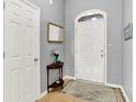 Neutral entryway featuring a front door with transom window, half-round table, and light wood floors at 7521 Kilbarron Cir, Indianapolis, IN 46217