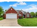 Charming single-story red brick home featuring an attached two-car garage and lush green lawn at 7521 Kilbarron Cir, Indianapolis, IN 46217
