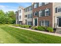 A manicured lawn leads to attractive townhomes featuring a mix of brick and siding exteriors at 9090 Demarest Dr, Fishers, IN 46038