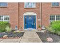 Close-up of a blue front door framed by brick, tasteful landscaping, and decorative yard ornaments at 9754 Bradford Knoll Dr, Fishers, IN 46037