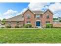Two-story brick home featuring a blue front door and complemented by a lush green lawn at 9754 Bradford Knoll Dr, Fishers, IN 46037