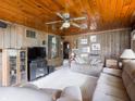 Spacious living room with wood paneled walls, ceiling fan, and plush sectional sofa at 10307 Wilson Rd, Brownsburg, IN 46112