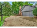 Attached two-car garage alongside a driveway and basketball hoop, surrounded by mature trees at 12961 Limberlost Dr, Carmel, IN 46033