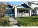 Charming blue home featuring a welcoming front porch and beautifully landscaped yard at 4231 Carrollton Ave, Indianapolis, IN 46205