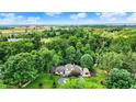 Aerial view showcases a luxurious home nestled among lush green trees against a blue sky at 4623 E Windsor Ln, Columbus, IN 47201