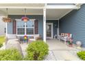 Inviting front porch with comfortable seating, hanging floral baskets, and charming welcome decor at 485 Thunderwood Dr, Greenfield, IN 46140