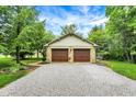 Two-car garage with stone accents and a wide gravel driveway, surrounded by mature trees at 4990 E County Road 750 S, Brownsburg, IN 46112