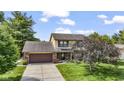 Two story home with brick and tan siding, long driveway, manicured lawn and mature landscaping at 5325 Ridge Hill Way, Avon, IN 46123