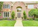 Elegant brick facade with arched entryway and landscaped walkway leading to front door at 5404 Cayman Dr, Carmel, IN 46033
