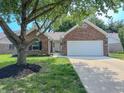 Traditional style brick home with an attached garage, mature trees, and a freshly sealed driveway at 6845 Arjay Dr, Indianapolis, IN 46217