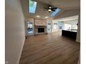 Open-concept living room featuring a fireplace, wood floors, and skylights for ample natural light at 6845 Arjay Dr, Indianapolis, IN 46217