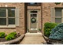 Inviting front entrance featuring a decorative wreath, potted plants, and a well-manicured landscape at 9804 Wentworth Ct, Carmel, IN 46032