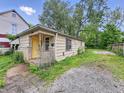 Exterior shot of a house with peeling paint, a yellow door, and an unkempt gravel yard at 1140 Mcdougal St, Indianapolis, IN 46203
