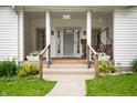 Inviting front porch with white columns, potted plants, and a charming porch swing at 1212 Woodlawn Ave, Indianapolis, IN 46203