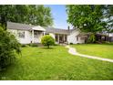 Quaint home featuring a large lawn, mature trees, and a concrete walkway at 1212 Woodlawn Ave, Indianapolis, IN 46203