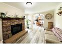 Inviting living room featuring a stone fireplace, light wood floors, and a view into the dining room at 125 W Church St, Thorntown, IN 46071