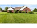 Beautiful brick home with lush green lawn and manicured landscaping offers a welcoming curb appeal at 1607 Michelle Manor, Danville, IN 46122