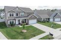 Aerial view of a well-manicured lawn, long driveway, and a charming two-story home in a suburban neighborhood at 1661 Devonshire Ave, Avon, IN 46123