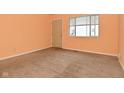 Bedroom with tan carpet, peach walls, a window, and a wooden door at 1802 Sugar Grove Ave, Indianapolis, IN 46202