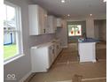 Kitchen with white cabinets, a kitchen island with sink, and views to the back yard at 1813 Real St, Indianapolis, IN 46240