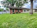 A well-maintained single story home with a lush green lawn and mature shade tree in the front yard at 1834 Chandler Ln, Columbus, IN 47203