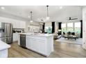 Bright, open kitchen with a stainless steel fridge, kitchen island, and adjoining living area at 18736 Moray St, Westfield, IN 46074