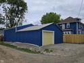 Blue, detached garage with a yellow garage door sits beside the home at 24 N Randolph St, Indianapolis, IN 46201
