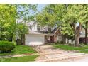 Inviting exterior of a brick and white home with a well-manicured lawn and mature trees at 2916 Sunmeadow Way, Indianapolis, IN 46228