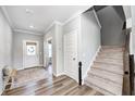 Bright foyer with a white door, hardwood floors, an open doorway, and staircase with carpeted steps at 3667 Gilmore Pl, Bargersville, IN 46106