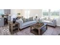 Bright living room with stylish sofas, wooden coffee tables, an area rug, and large windows with natural light at 3928 Riverstone Dr, Whitestown, IN 46075