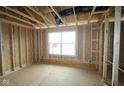 Unfinished new bedroom with a window, framing, and visible studs showcasing the construction phase at 4947 Amber Crest Dr, Brownsburg, IN 46112