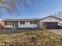 Charming one-story home with white siding, brown shutters, and an attached garage at 619 Belzer Dr, Anderson, IN 46011