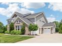 Side view of a two-story home with brick, siding, attached garage, and long driveway at 644 Ridge Gate Dr, Brownsburg, IN 46112