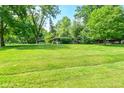 Landscaped front yard with mature trees and green grass surrounding the home at 6550 Sunset Ln, Indianapolis, IN 46260
