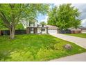 Two-story home features a well-manicured lawn, mature trees, a driveway, and an attached garage at 8416 Buckingham Dr, Columbus, IN 47201