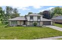 Charming two-story home featuring stone accents, gray shingles, a well-manicured lawn, and attached garage at 10502 E Lakeshore Dr, Carmel, IN 46033