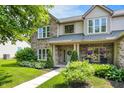 Inviting covered porch with brick columns and a seating area, framed by lush greenery and well-kept lawn at 10965 Fairway Ridge Ln, Fishers, IN 46037