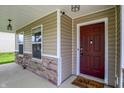 Close-up of the front entrance with a stylish maroon door, stone accents, and a welcoming welcome mat at 11437 High Grass Dr, Indianapolis, IN 46235
