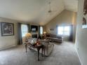Spacious living room featuring vaulted ceilings, a fireplace, neutral carpet, and large windows at 11621 Coastal Dr, Indianapolis, IN 46229