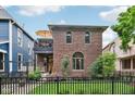 Charming brick home featuring a balcony, arched windows, and a well-manicured lawn with black fence at 1436 Central Ave, Indianapolis, IN 46202