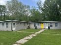 View of a multi unit building featuring neutral siding, a bright yellow front door, and lawn at 1642 W 6Th St, Anderson, IN 46016