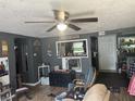 Cozy living room with ceiling fan, grey walls, and view into kitchen at 1642 W 6Th St, Anderson, IN 46016