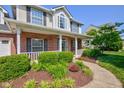 Close up of a charming two-story home with a manicured front garden and inviting front porch at 2234 Burgundy Way, Plainfield, IN 46168