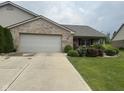 Charming brick home with an attached garage and driveway, complemented by neat landscaping at 2916 Wind Chime Cir, Greenwood, IN 46143