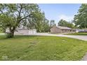 Well-maintained front yard with a brick home, gravel driveway, and a spacious outbuilding, perfect for storage at 312 W Clark Ln, Fairland, IN 46126