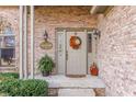 Inviting front entrance with brick wall, fall wreath, seasonal decorations, and lush greenery at 3819 S Village Dr, New Palestine, IN 46163